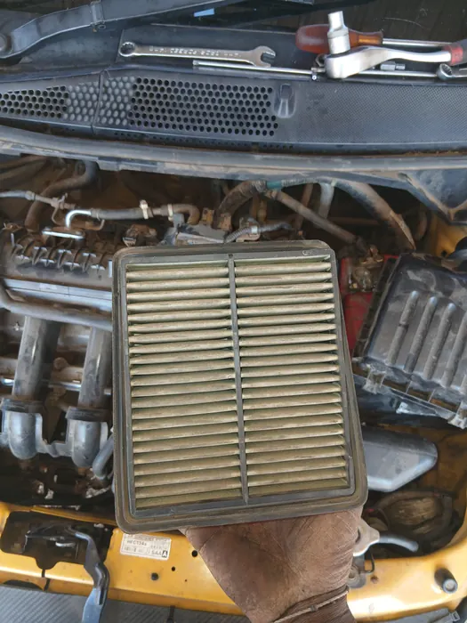 A dirty air filter held up above the engine